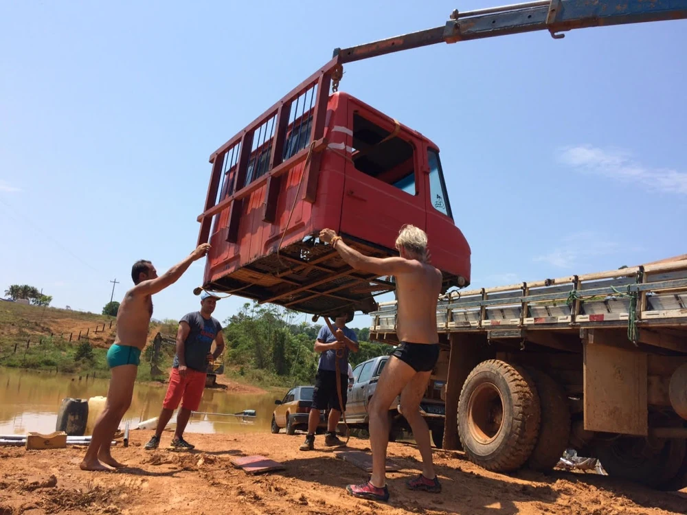 Caminhão e pessoas acompanhando a movimentação de um veículo com cabos.